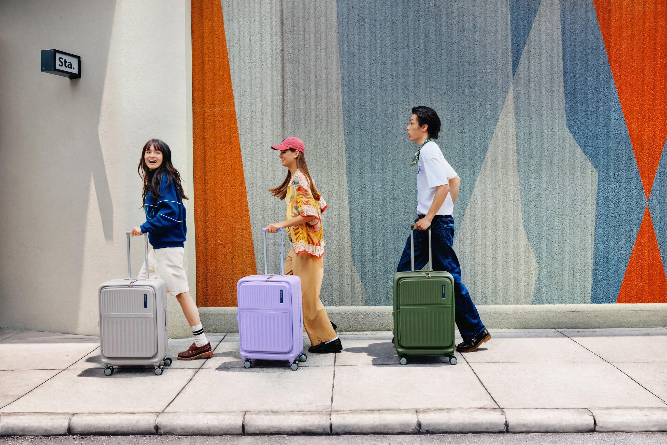 Three travellers walking a city street with colourful luggage